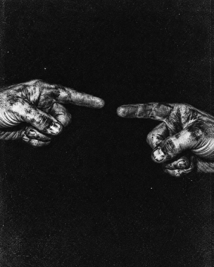 Grainy black and white photo of two dirty hands pointing at each other